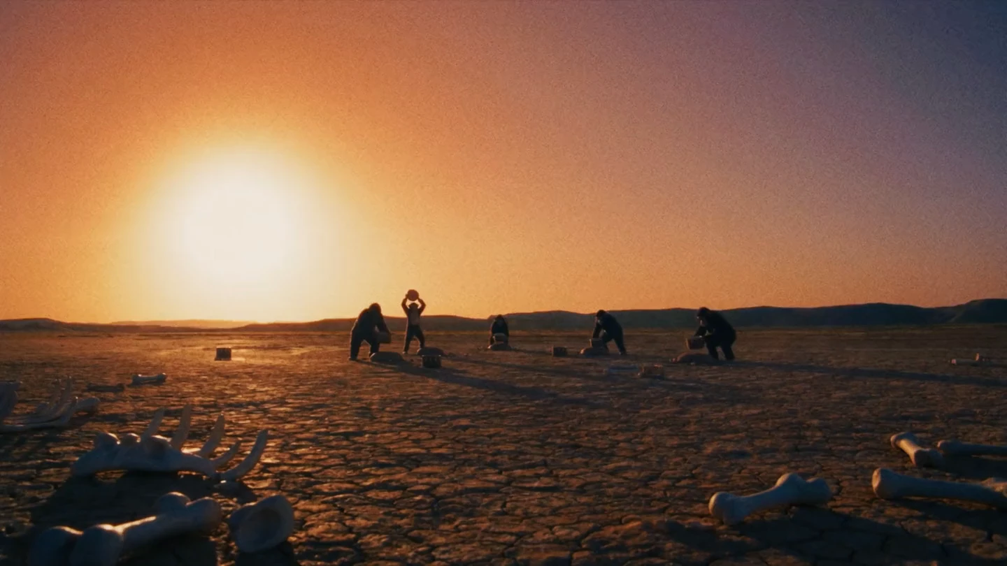 Apes silhouetted against a low sun on an empty plain